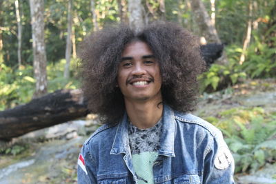 Portrait of smiling man with frizzy hair in forest