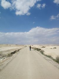 Rear view of woman walking on road against sky