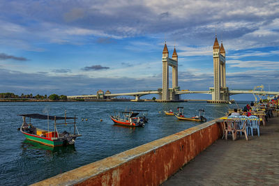 Boats in sea against cloudy sky