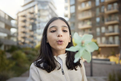 Girl blowing on pinwheel outdoors