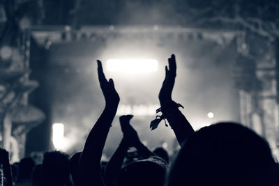 Close-up of silhouette hands against sky at night