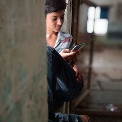 Boy holding mobile while sitting