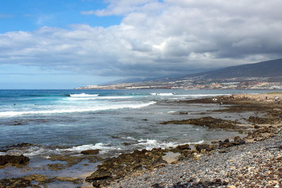 Stony beach at playa de las americas on canary island tenerife with blue water