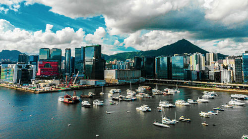 Sailboats in city by sea against sky