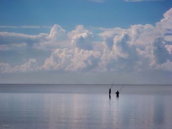 People fishing in sea against sky