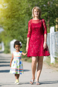 Portrait of smiling mother with daughter walking on road