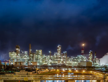 Illuminated factory against sky at night