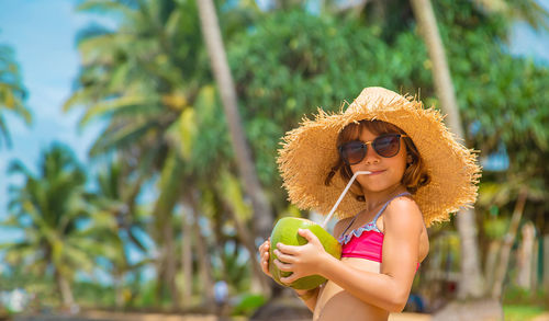 Portrait of girl with straw hat drinking coconut water at home