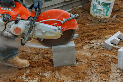 Low section of person cutting concrete block with machinery