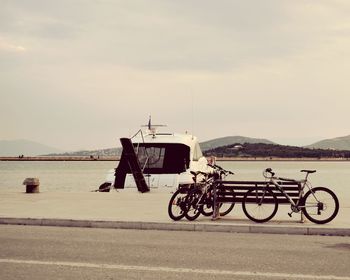 Bicycles on road by sea against sky