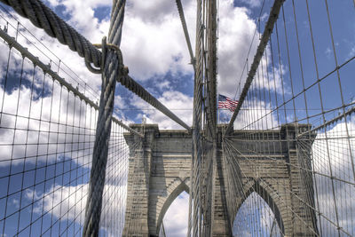 Low angle view of suspension bridge against cloudy sky