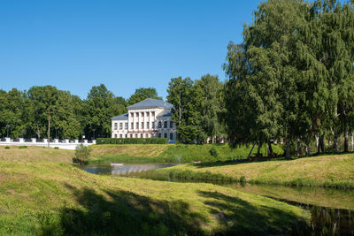 Trees and houses on field against clear sky