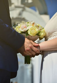 Midsection of bride holding bouquet