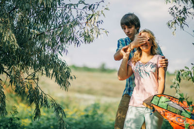 Happy young couple walking on field against sky