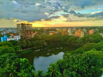 Scenic view of river by buildings against sky during sunset