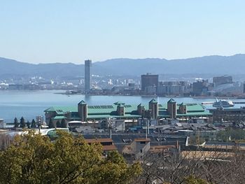 High angle view of cityscape by sea against clear sky