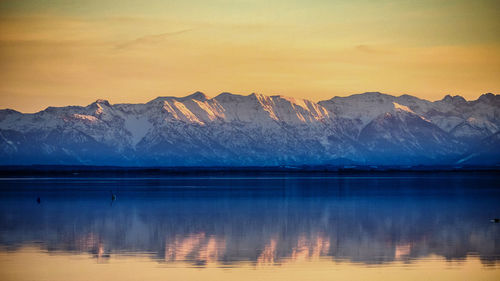 Scenic view of lake by mountains against sky during winter