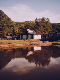 House by lake against sky