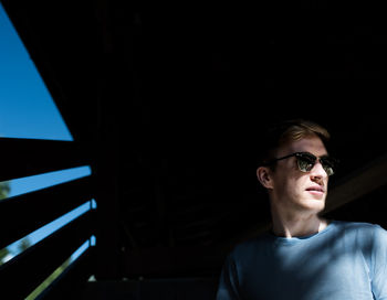 Sunlight falling on young man wearing sunglasses in hut