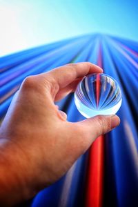 Cropped hand of person holding crystal ball against pattern