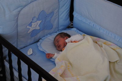 High angle view of child lying in crib
