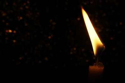 Close-up of lit candle in darkroom