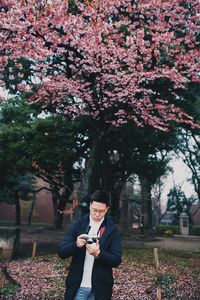 Young man with camera standing at park during winter