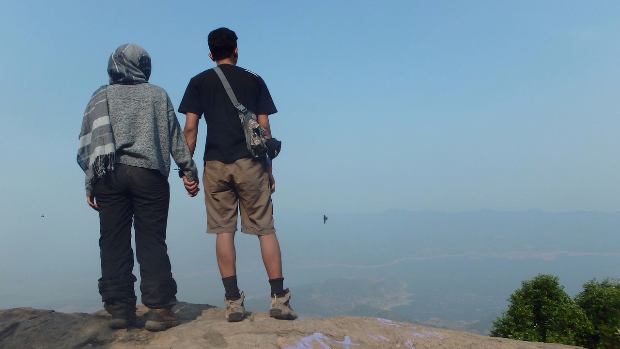 lifestyles, leisure activity, men, standing, full length, rear view, clear sky, casual clothing, water, person, vacations, mountain, togetherness, tourist, copy space, tranquility, nature