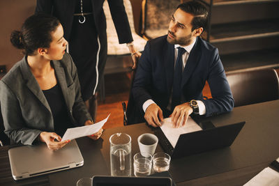 High angle view of male and female colleagues discussing with financial advisor at office meeting