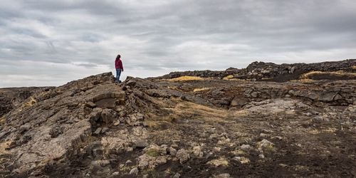 Woman standing on rock against sky