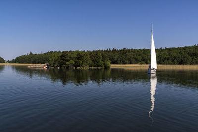 Sailboat on rippled lake against clear blue sky