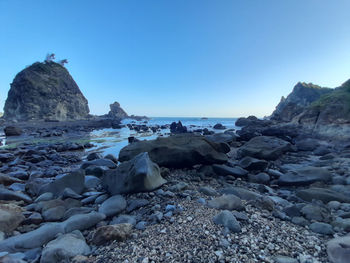 Rocks on beach against clear blue sky