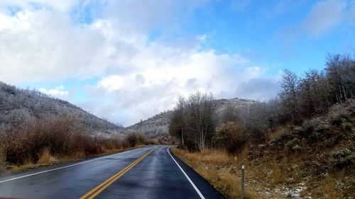 Road amidst trees against sky