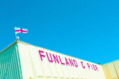 Low angle view of flags sign against clear blue sky