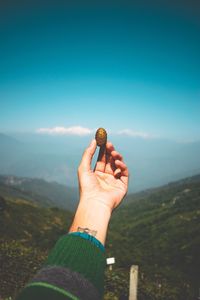 Midsection of person holding hand against mountain