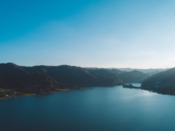 Scenic view of lake and mountains against blue sky