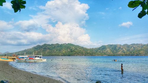 Boats in sea against cloudy sky