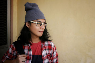 Portrait of beautiful young woman standing against wall