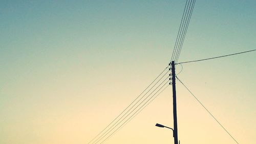 Low angle view of electricity pylon against clear sky