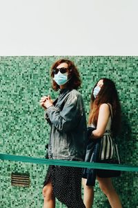 Woman wearing sunglasses standing against wall