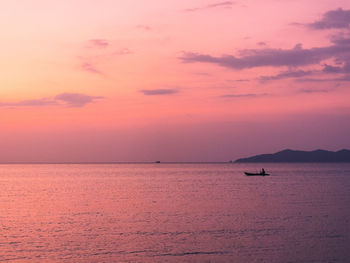 Scenic view of sunset orange sky at peaceful sea bay with lonely kayak. koh mak island, thailand.