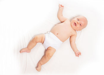 High angle view of smiling baby lying on bed at home