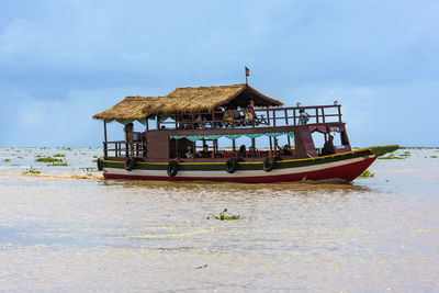 Stilt house by sea against sky