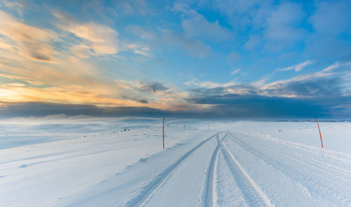 Scenic view of snow covered landscape against blue sky during sunset