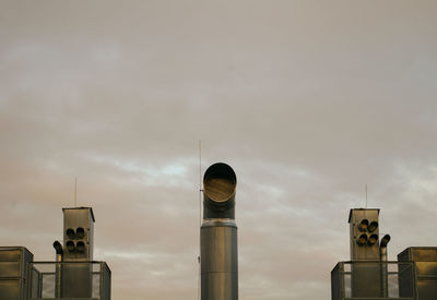 Low angle view of air duct pipes against sky in industry