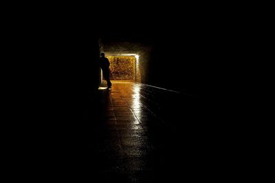 Silhouette man walking in illuminated dark room