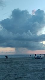 People on beach against sky during sunset