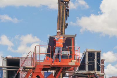 Low angle view of man working at construction site against sky