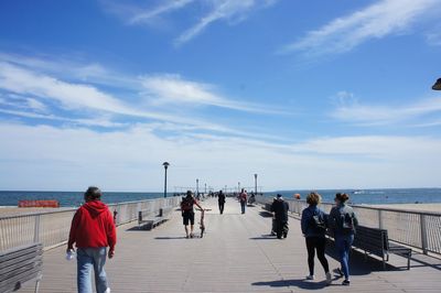 People walking on pier against sky