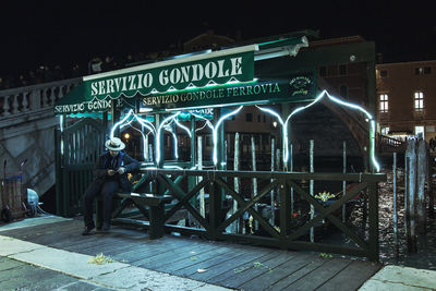 Man on illuminated bridge in city at night